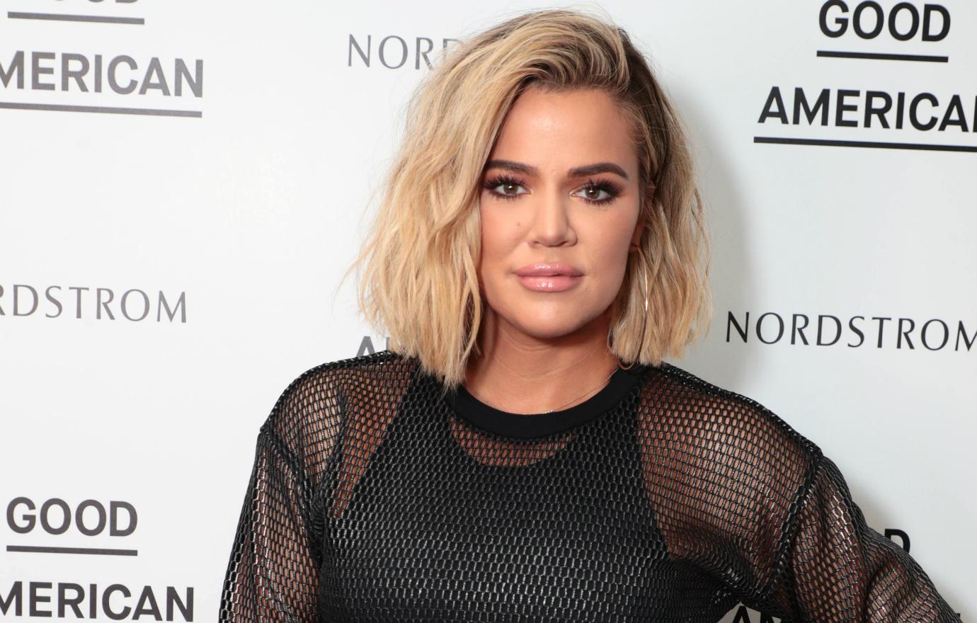 Khloe Kardashian in a black mesh top on the red carpet.