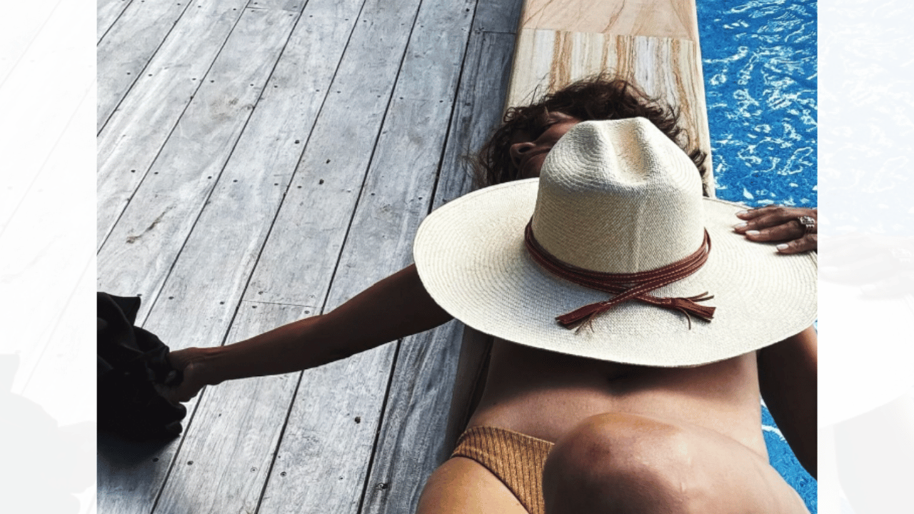 Image of Halle Berry covered her assets with a hat as she relaxed topless. 