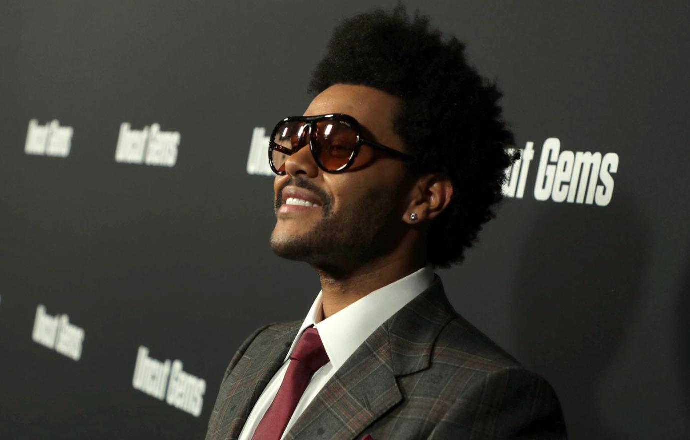 Singer The Weeknd looked dapper in a grey plaid striped suit with a maroon tie draped over a white oxford.