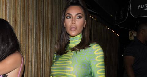 Kim Kardashian wears a figure-hugging green dress with a yellow design on it.