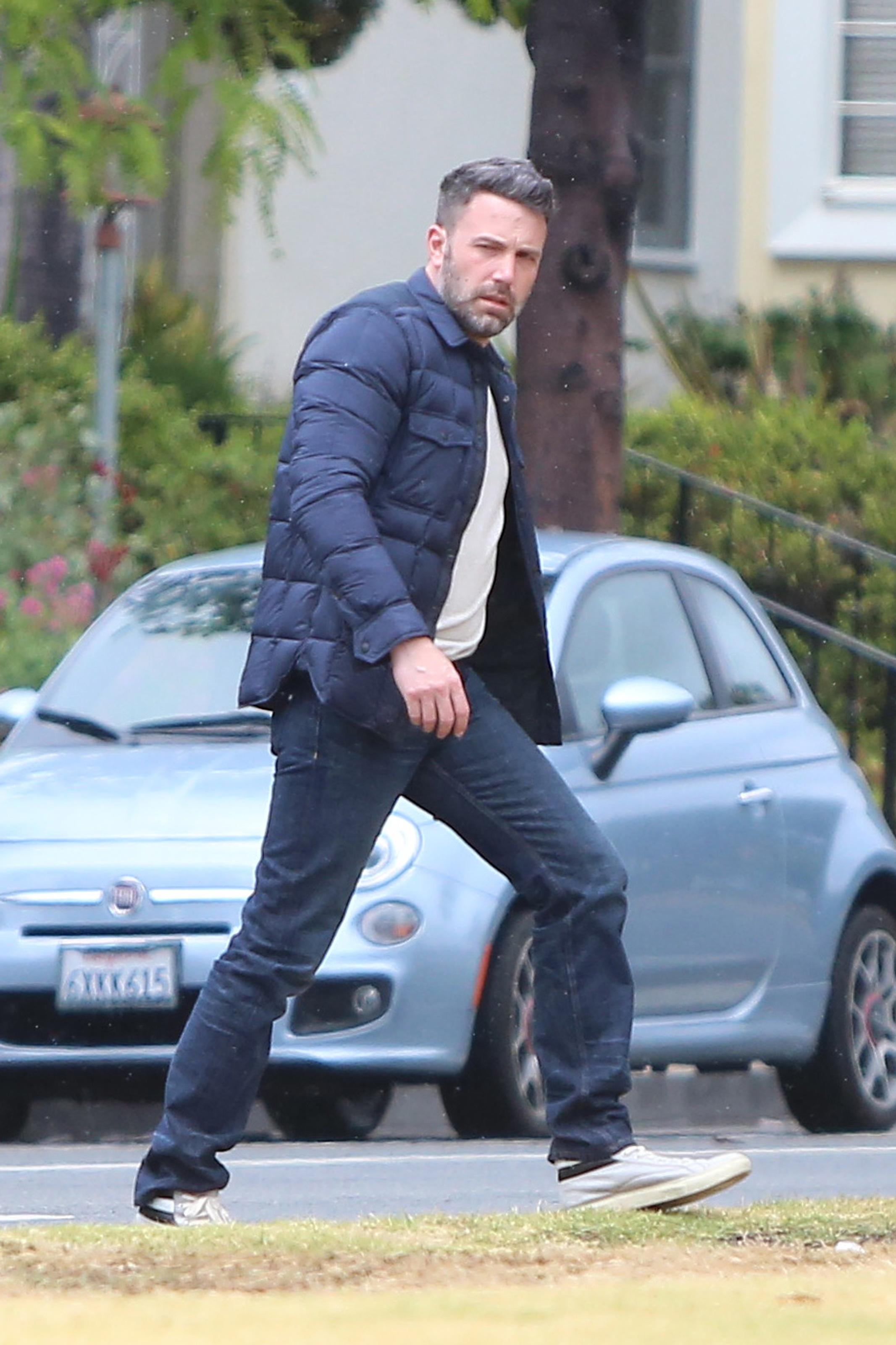 A scruffy Ben Affleck jaywalks in the rain