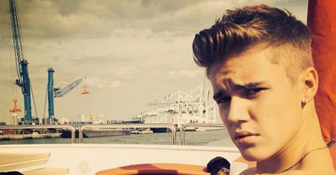 Justin Bieber sits in front o water while looking at the camera.