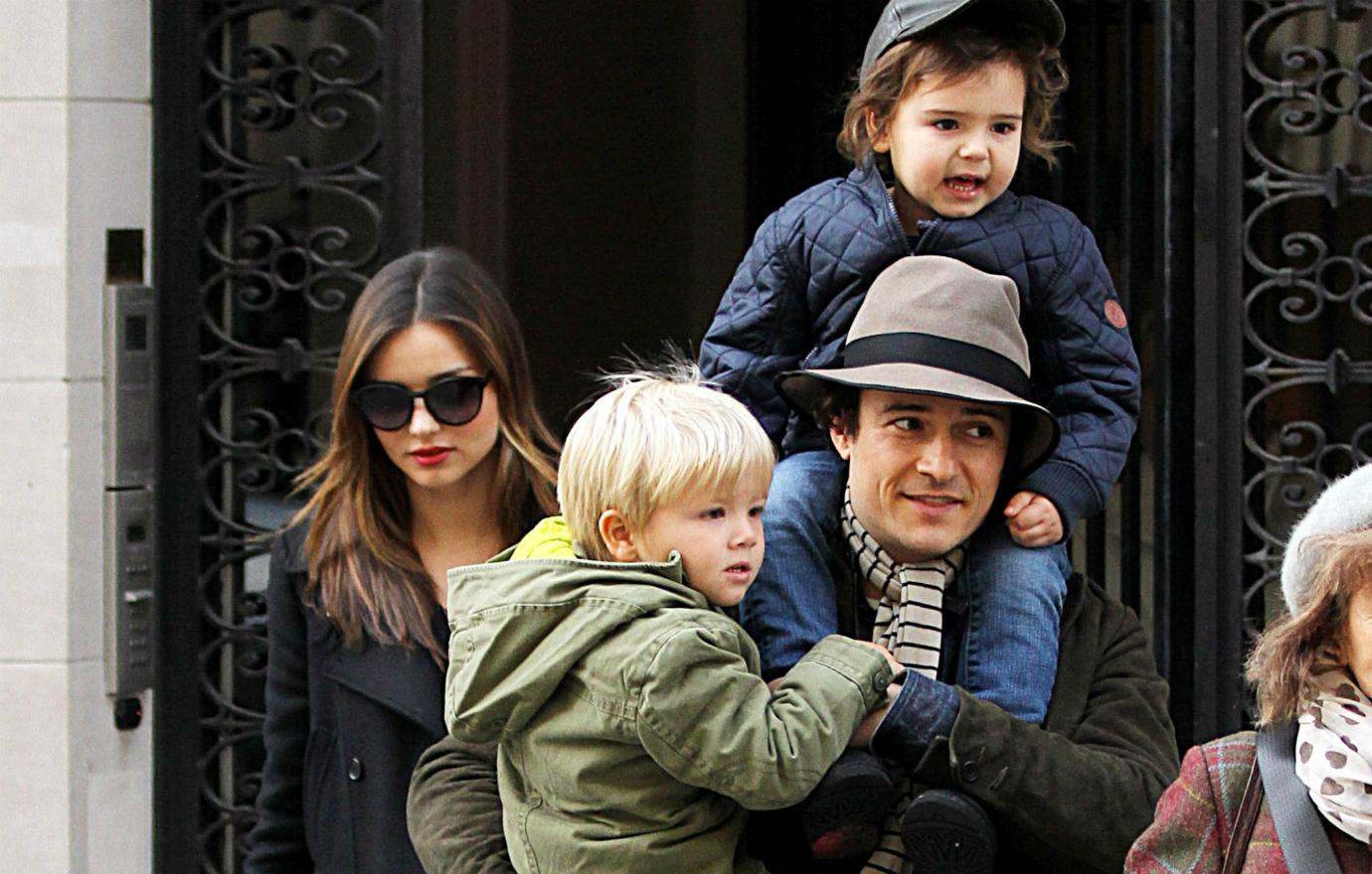 Orlando Bloom holds his kid, Miranda Kerr by their side.