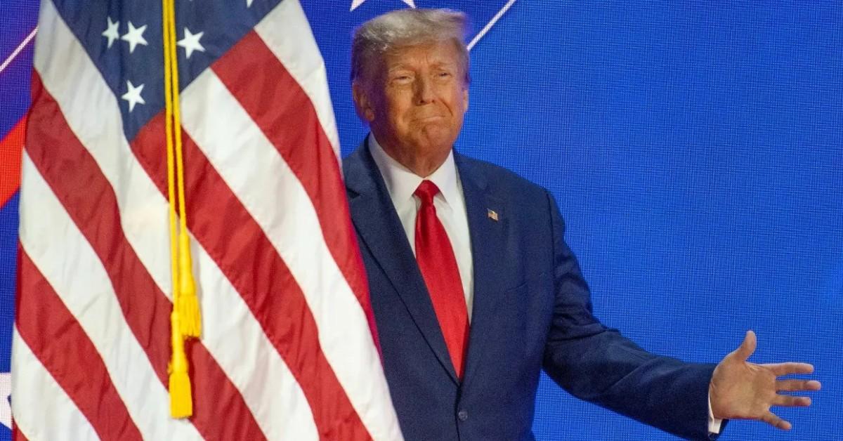 Photo of Donald Trump standing next to flag.