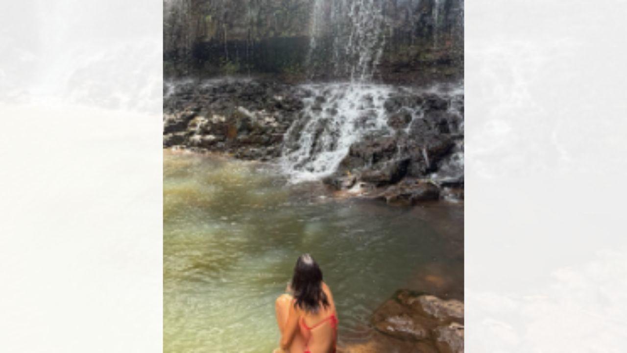 Image of Kendall Jenner sat in front of a waterfall in a red string bikini.