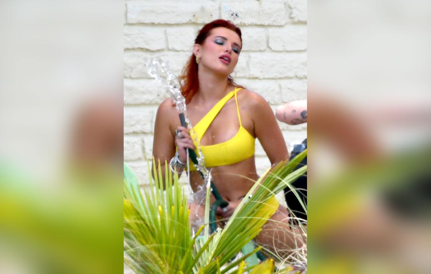 bella thorne wears yellow bikini as she poses seductively with a water hose during a photoshoot in miami ok