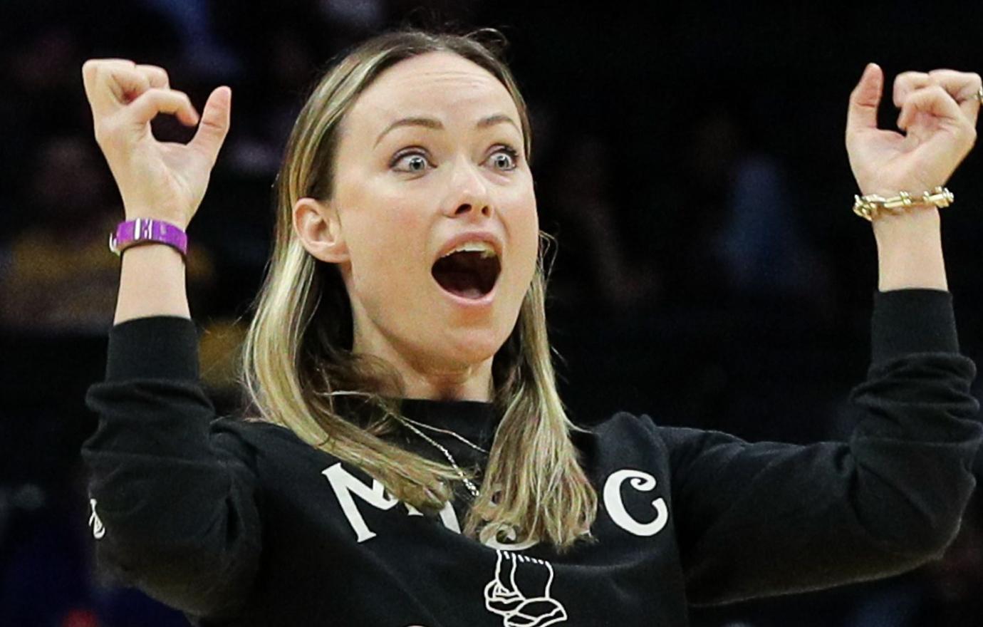 Olivia Wilde looked shocked as she shot a basket at a Harlem Globetrotter game as she wore black jeans and a black sweatshirt that said, “Magic Saves.”