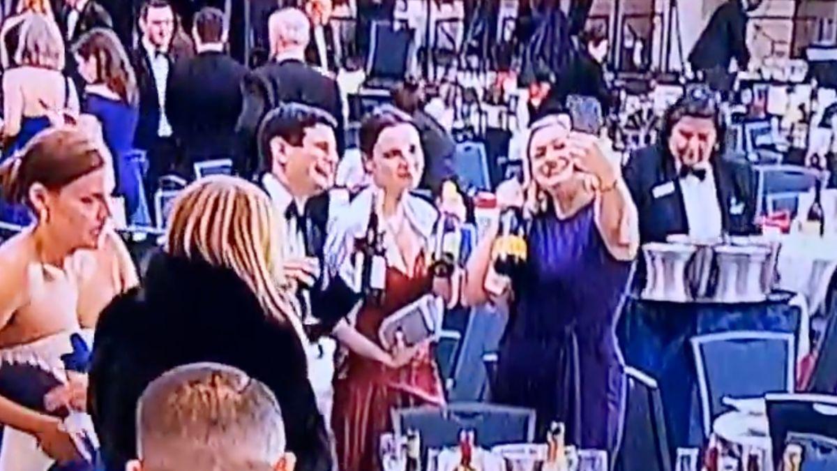 image of Guests posed with bottles of wine abandoned on tables at the dinner.