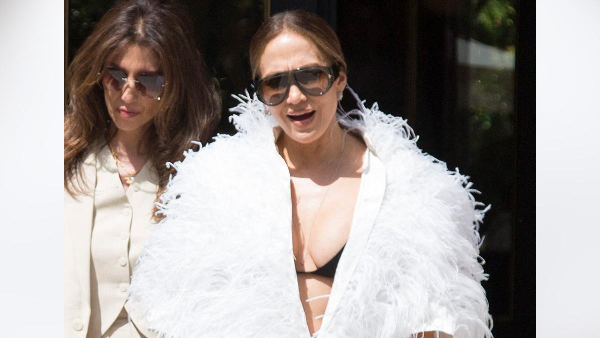 image of Jennifer Lopez turned heads in Paris by wearing a dramatic white feather coat that revealed a glimpse of her black bralette during Haute Couture Week.