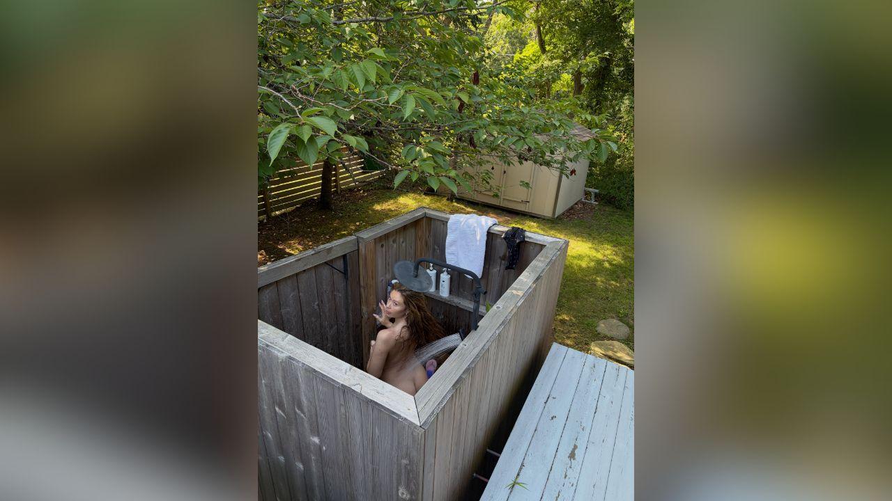 image of Gabby Windey shared a playful photo of herself beneath an outdoor shower surrounded by greenery.