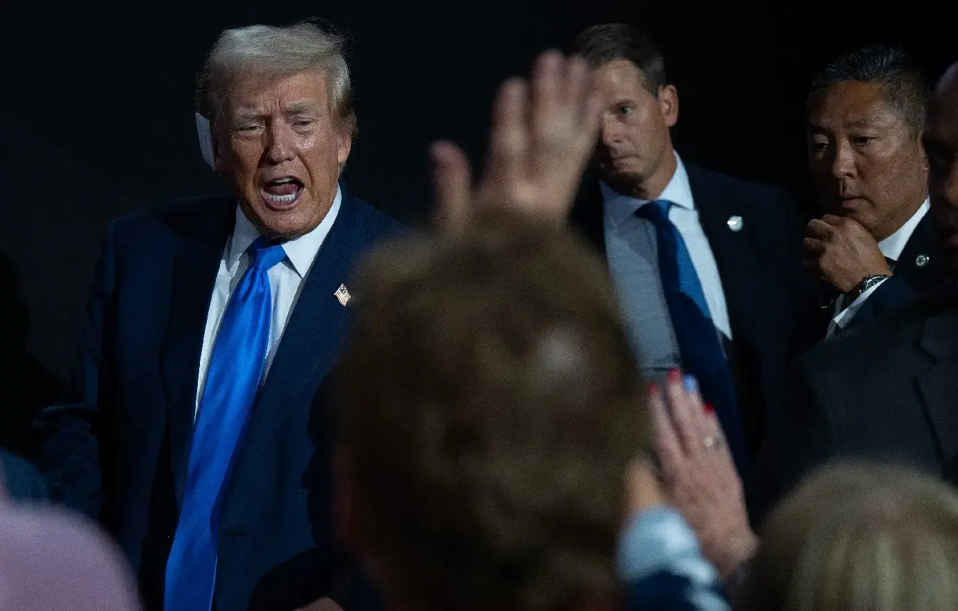 Photo of Donald Trump walking in crowd with bandage on his ear.