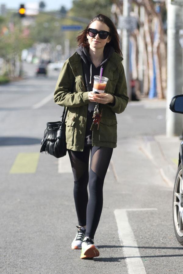 Lily Collins walks back to her car with a cold drink after her workout