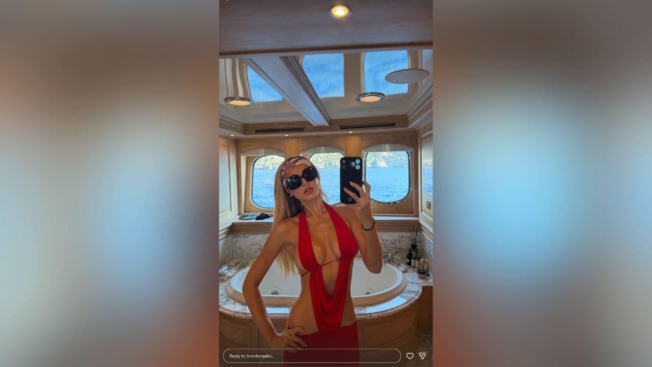 image of Brooks Nader was photographed aboard a luxury boat in Italy wearing a bright red bikini with cutouts and a plunging design.