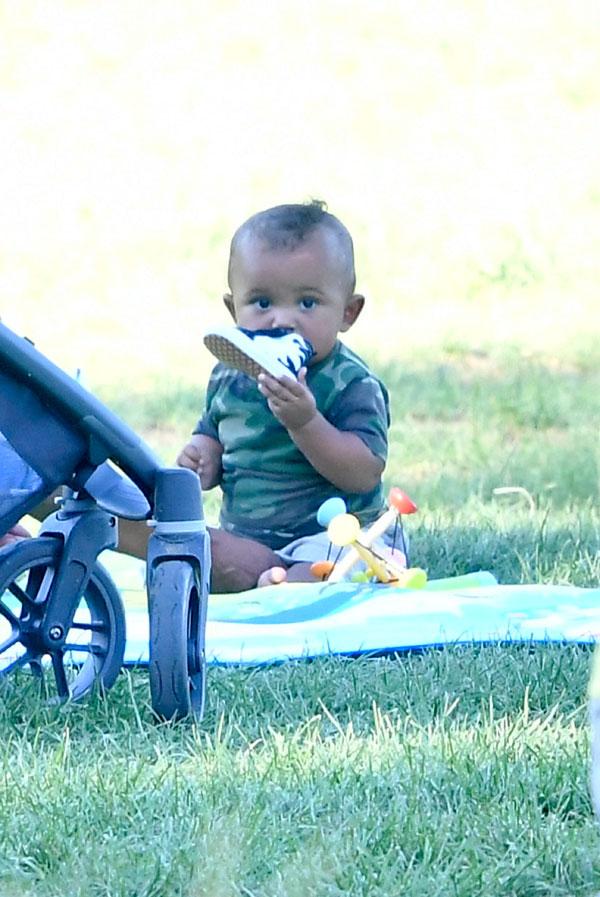 saint west smelling shoe laughing having fun in the park