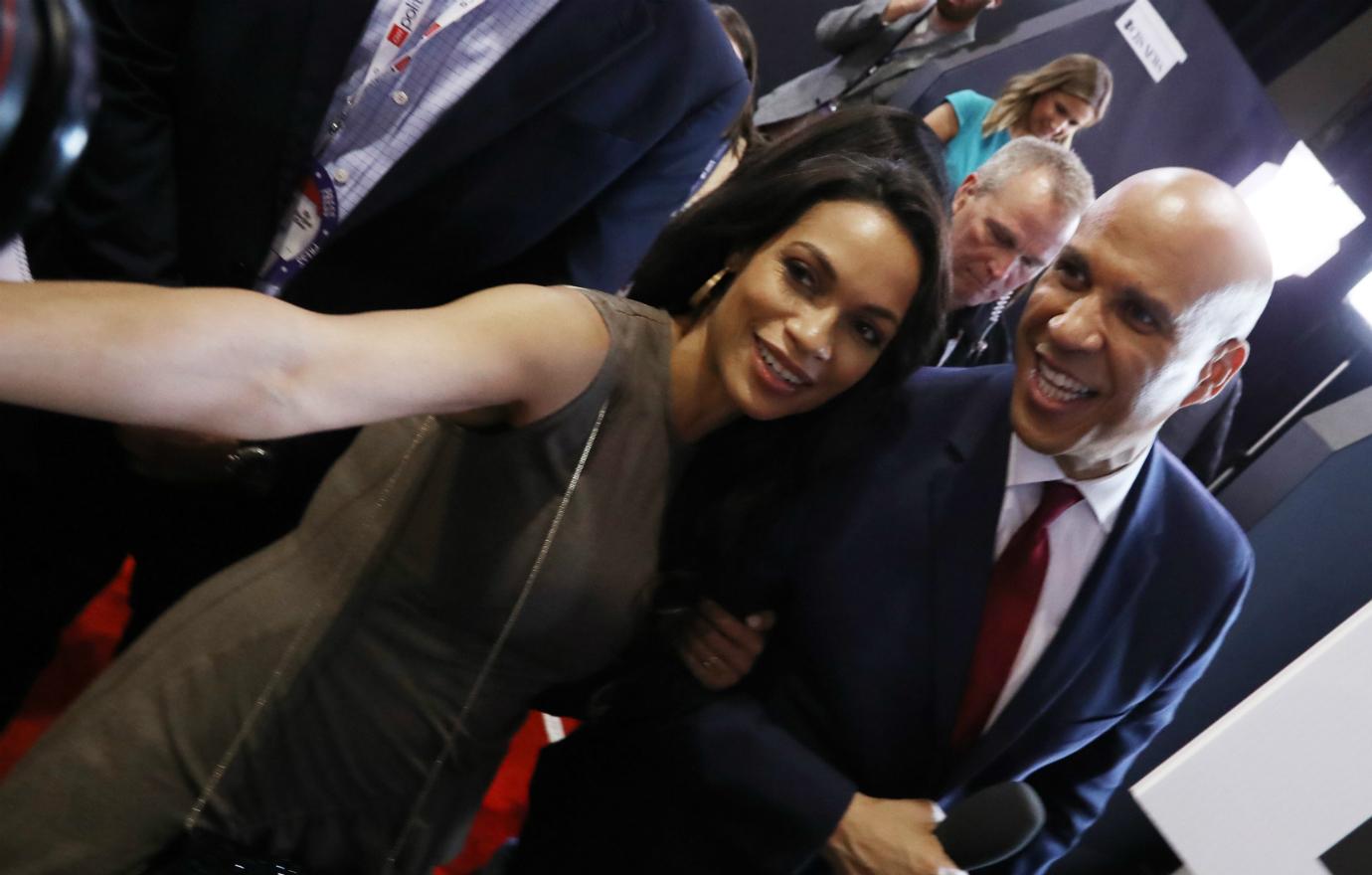 Rosario Dawson and Cory Booker pose for a selfie that Rosario is taking on the red carpet.