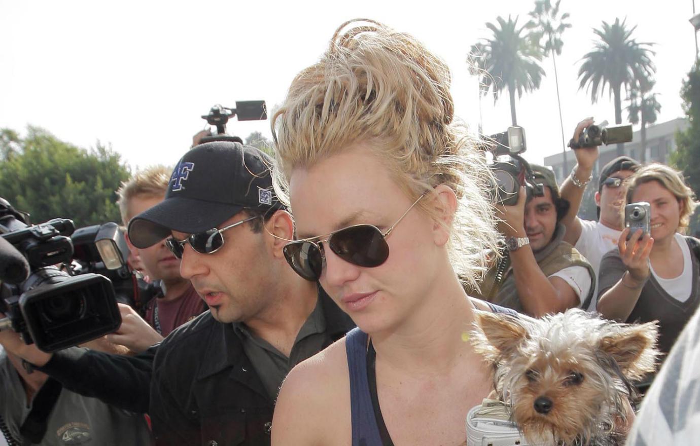 Britney Spears was photographed by paparazzi in a blue tank top and Ray Ban aviator shades with her pup.