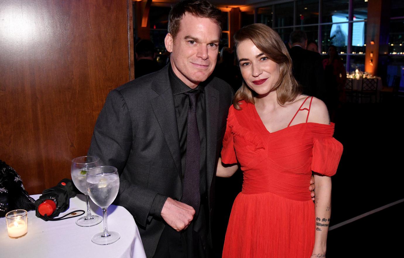 Michael C Hall in black suit wih wife Morgan MgGregor in red.