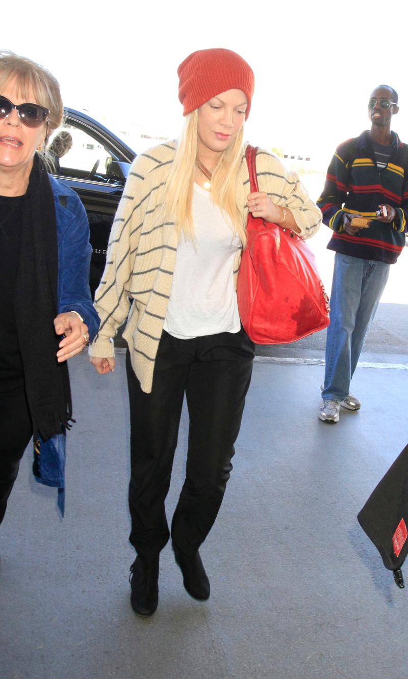 Tori Spelling has a major spill in her designer handbag that seeps right through before her flight out of LA.