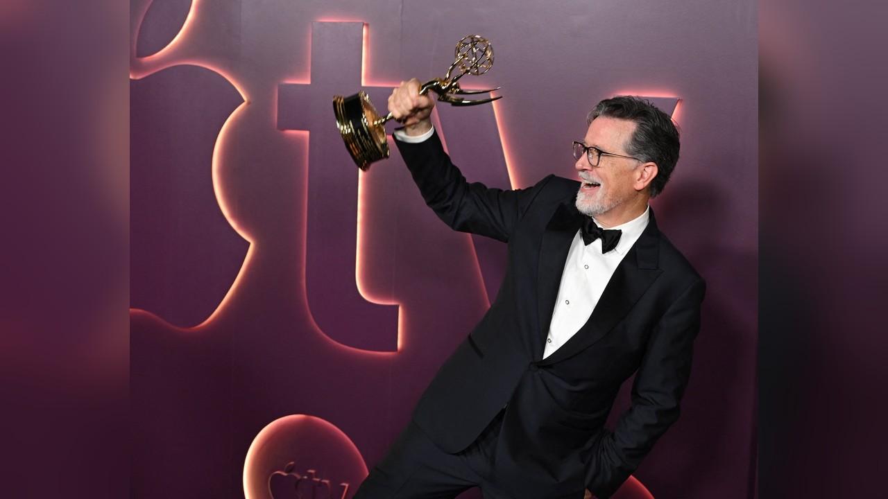Image of Stephen Colbert triumphantly raised his Emmy while celebrating his victory after television's biggest night.