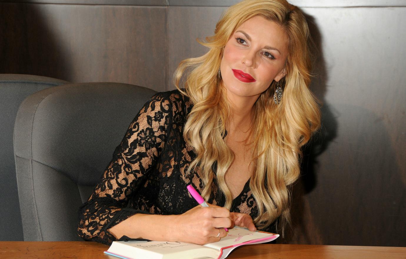 Brandi Glanville wears a black lacy top and loose wavy hair while signing copies of her book Drinking & Dating in 2014.