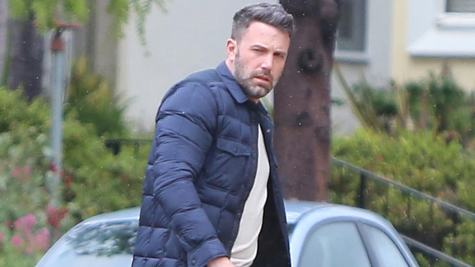 A scruffy Ben Affleck jaywalks in the rain