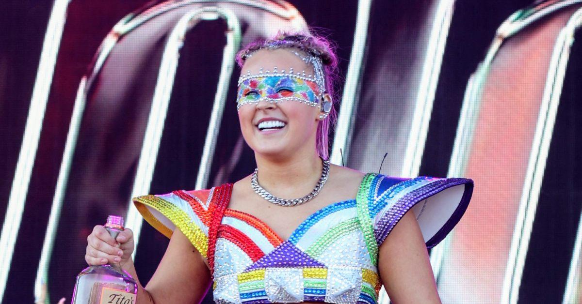 Photo of JoJo Siwa onstage holding a jug of vodka.