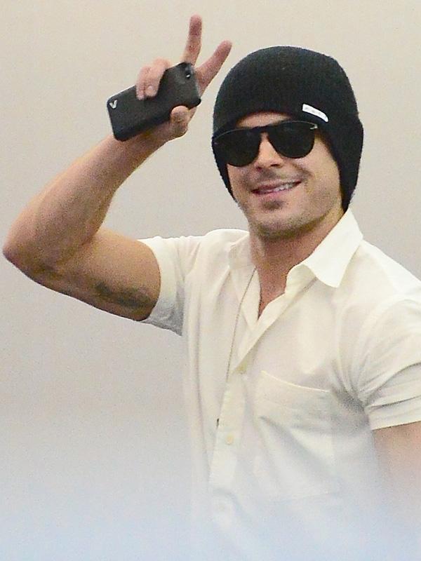 Zac Efron and Seth Rogen take selfies with fans before boarding a flight at JFK Airport