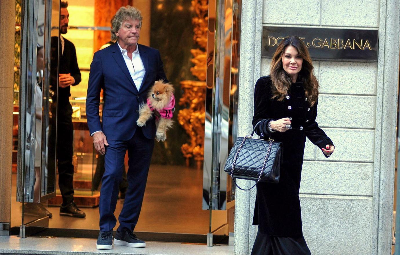 Lisa Vanderpump, in black and clutching an oversized purse, leaves a store with her husband and dog in tow.