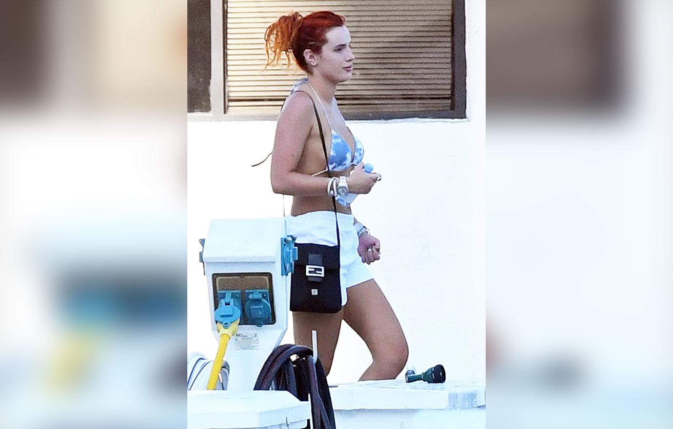 bella thorne wears a blue and white bikini as she holds hands with fiance benjamin mascolo while getting off a yacht