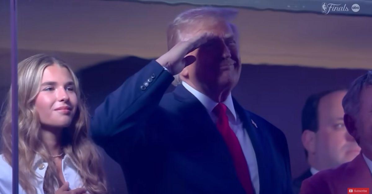 image of Donald Trump stood with his hands at his sides during much of the national anthem before later raising his hand in a salute.