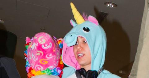 Miley Cyrus wears a onesie and carries a pink seahorse through Sydney Airport