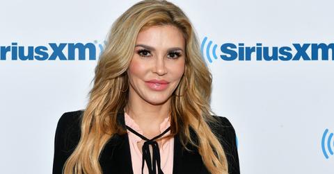Brandi Glanville wears a black top with strings tied in a bow over a pink top in this 2018 SiriusXM Studios visit.