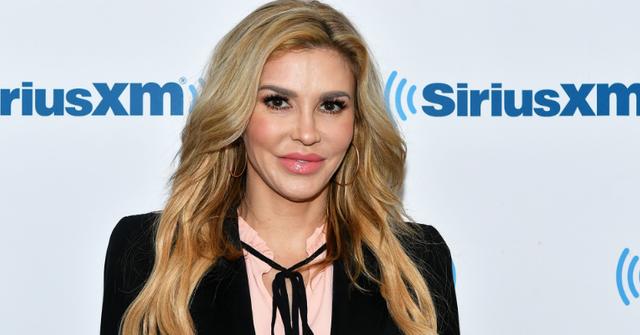 Brandi Glanville wears a black top with strings tied in a bow over a pink top in this 2018 SiriusXM Studios visit.