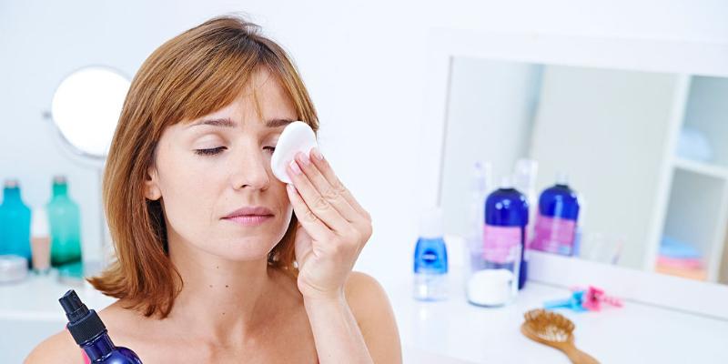 A young woman applying makeup remover to the eyes