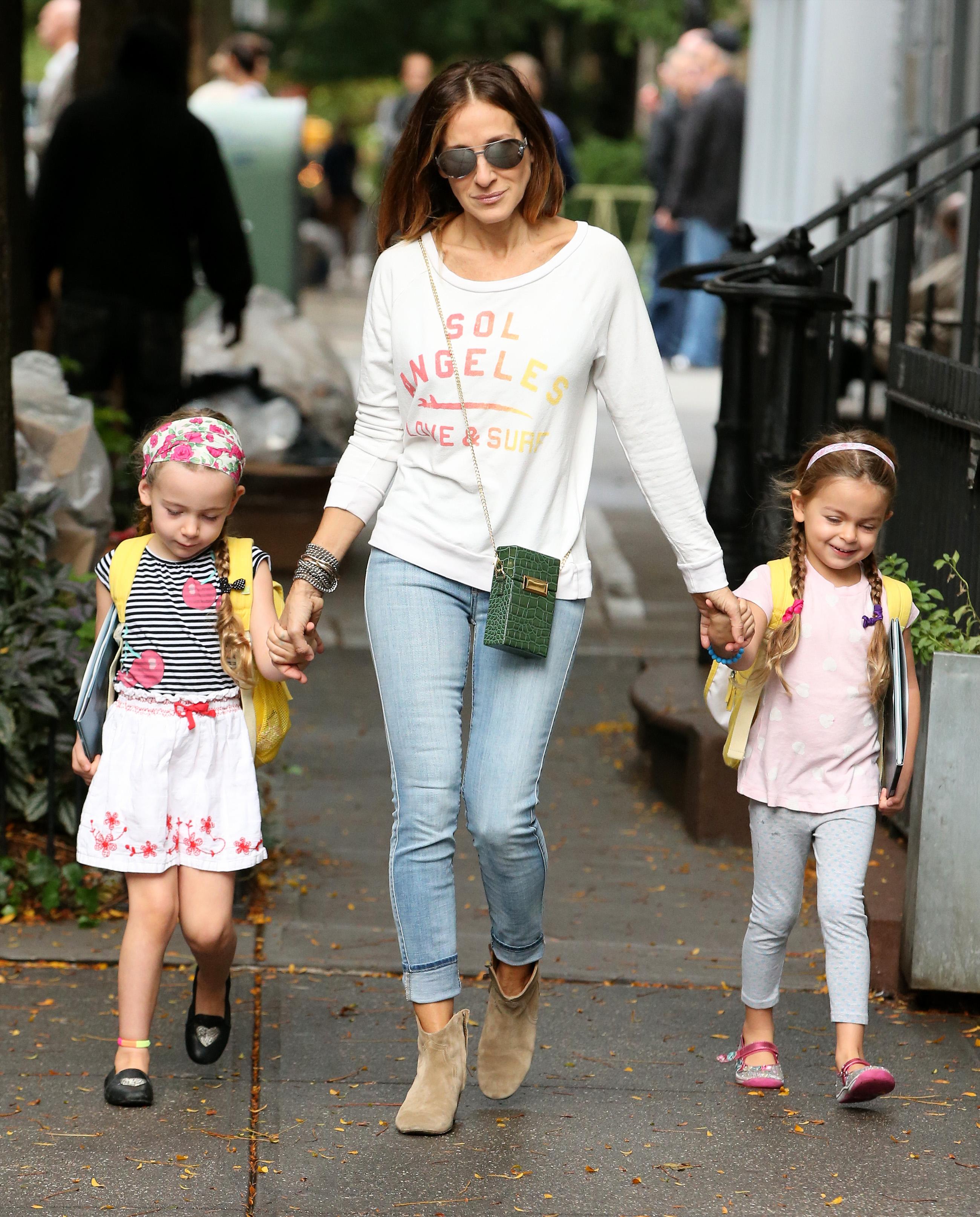 Actress Sarah Jessica Parker walks with her twin daughters Marion and Tabitha Broderick, wearing matching yellow backpacks with smiley faces, in West Village, NY