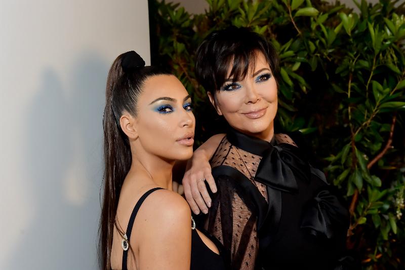 Kim Kardashian wears a black outfit and high ponytail with dramatic eye makeup, posing alongside mom Kris Jenner at the 2018 KKWxMario dinner in Beverly Hills.