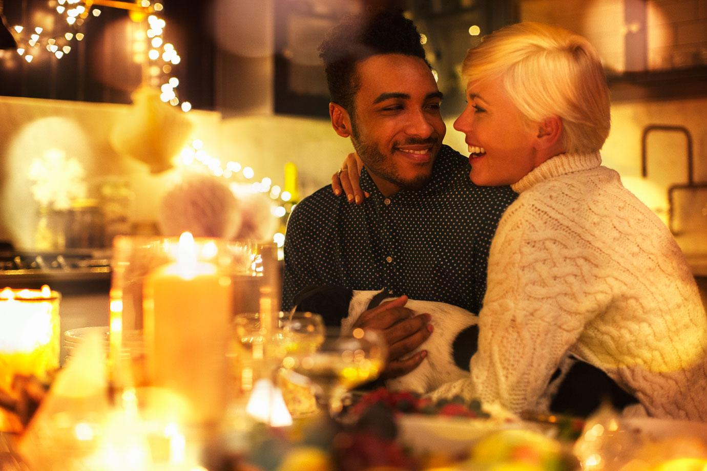 Affectionate couple with dog at candlelight Christmas table