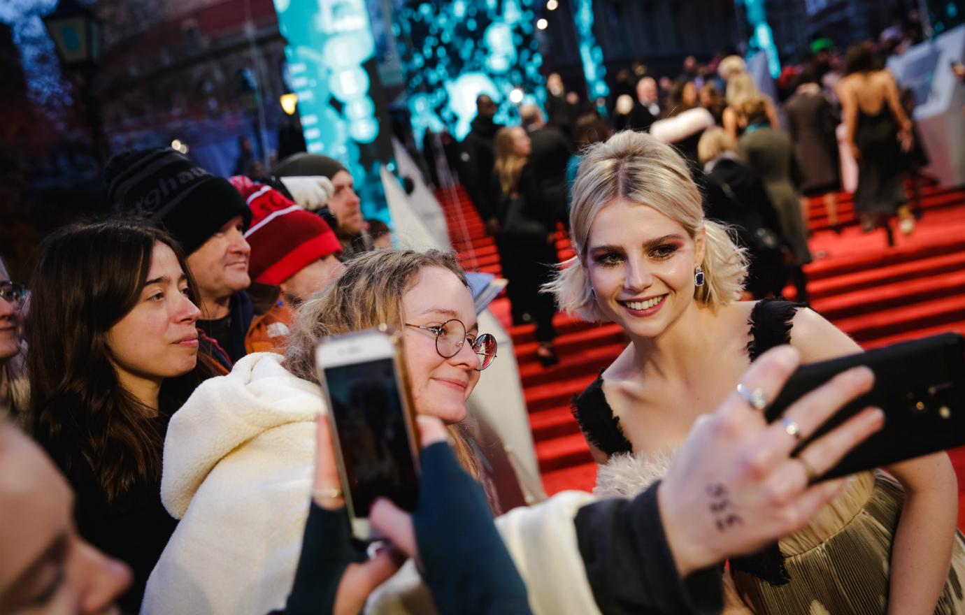 Lucy Boynton poses with fans on the red carpet.