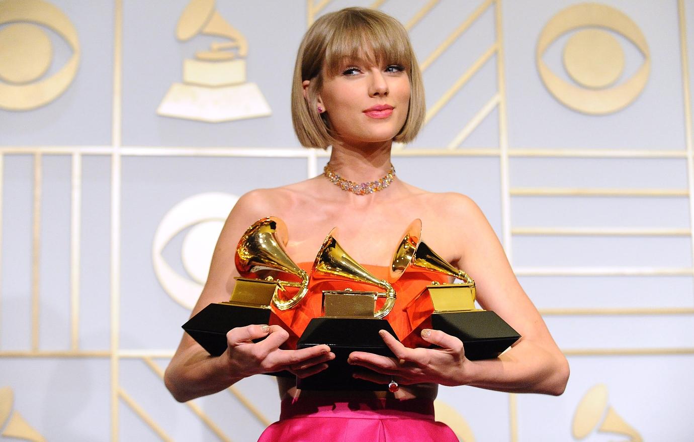 Taylor Swift holding a handful of Grammys