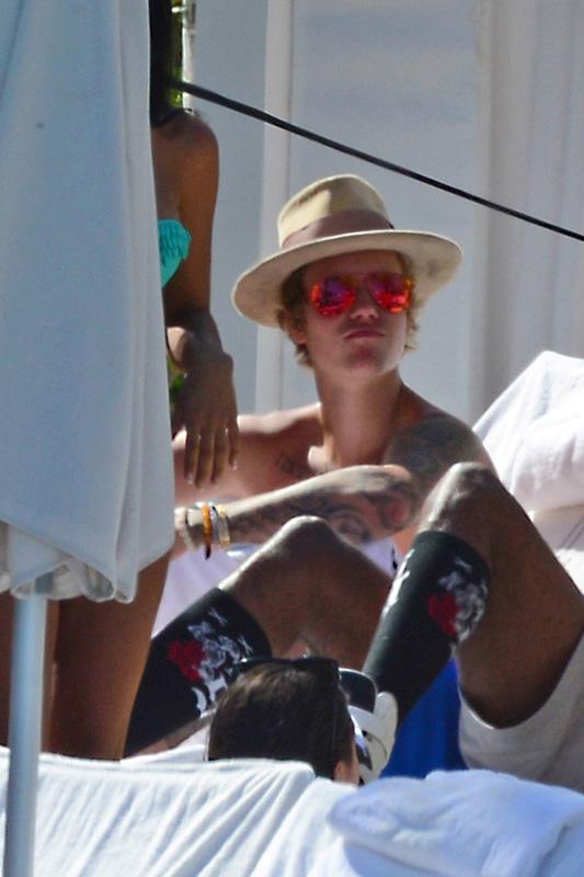 A heavily tattooed Justin Bieber kicks up his feet and relaxes poolside in Miami **USA ONLY**