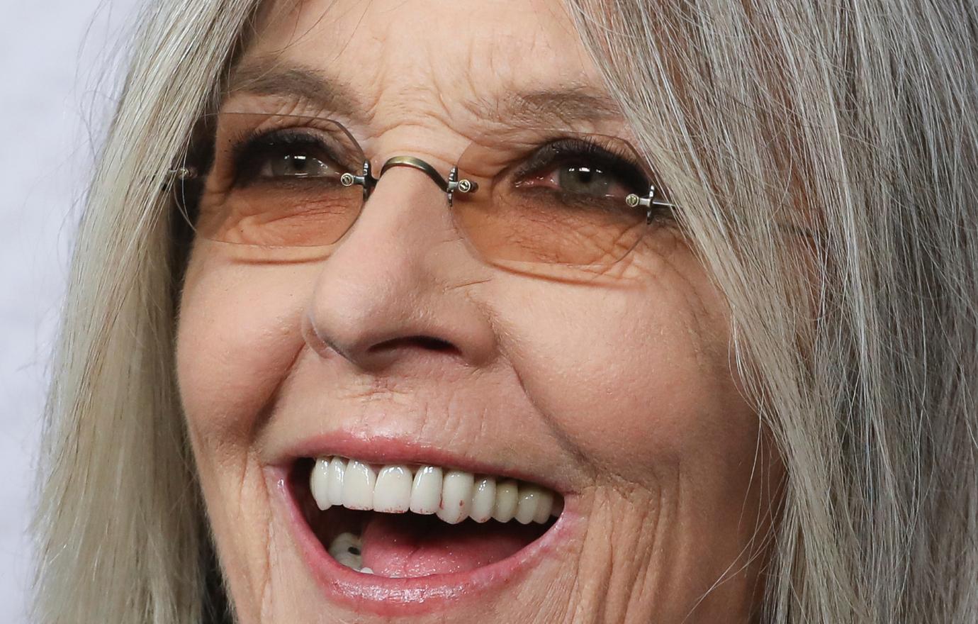 Diane Keaton attended a red carpet event with tinted rose glasses and a black turtleneck underneath her black, grey and white patterned outercoat.