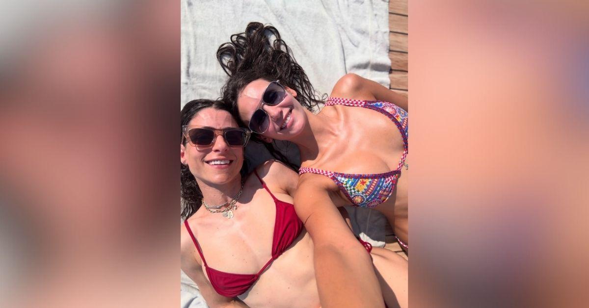 image of Nina Dobrev stunned in a tiny bikini while lounging poolside with her friend.