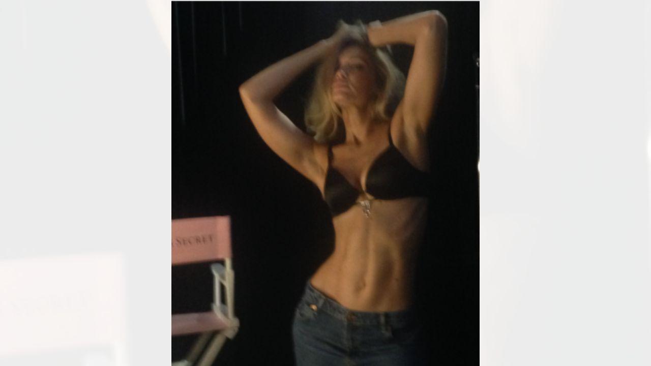 Image of Gigi Hadid posed backstage in her bra and a pair of low-rise jeans.