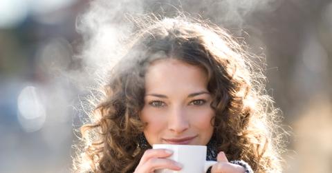 Brunette woman in pullover drinking hot tea