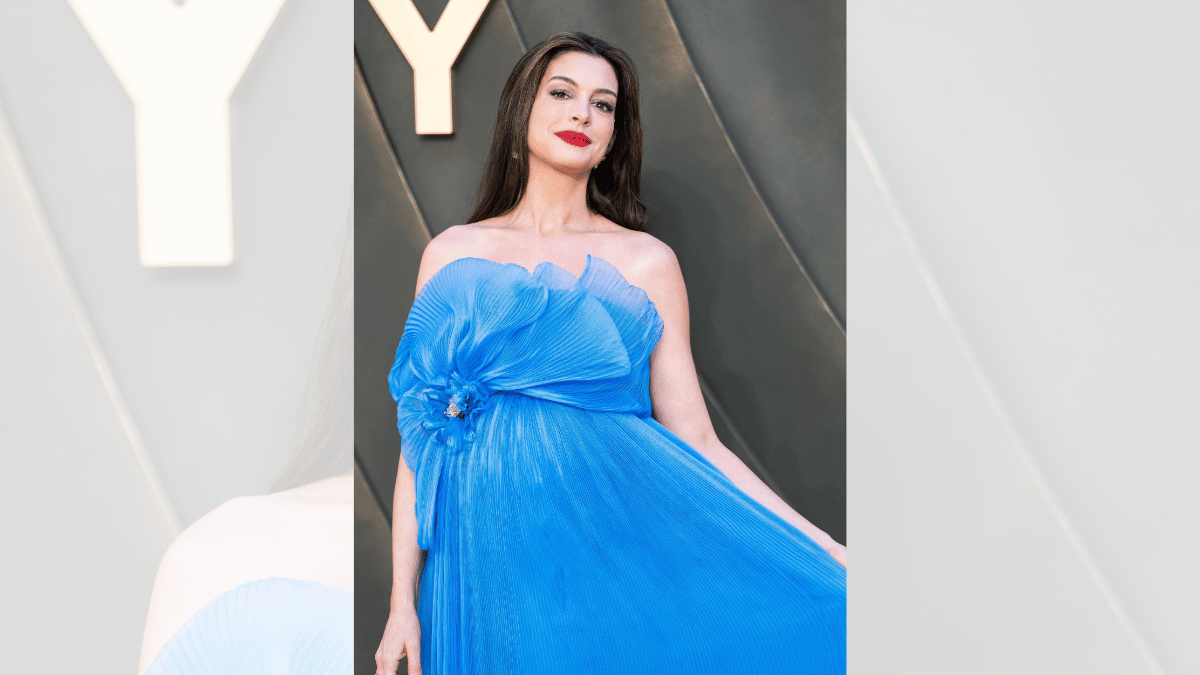 Image of Anne Hathaway smiled as she gently held her baby bump while posing on the red carpet at 'The Odyssey' world premiere in London.