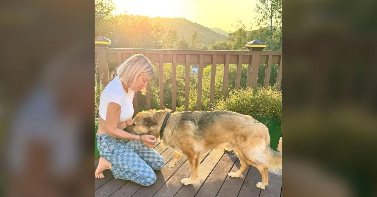 Image of Tori Spelling cuddled up to her dog on the patio.