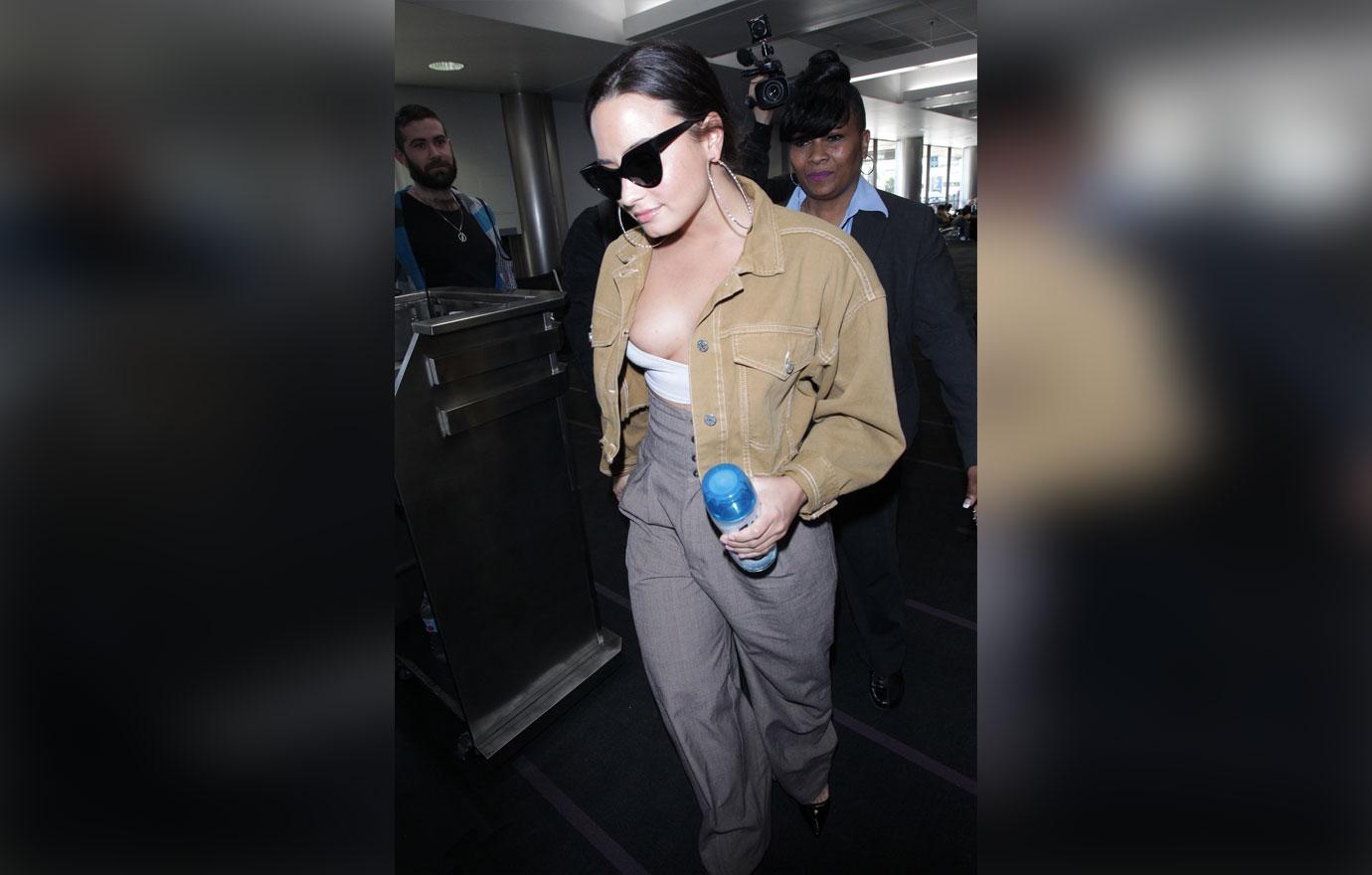 Demi Lovato hangs out of her top as she departs LAX