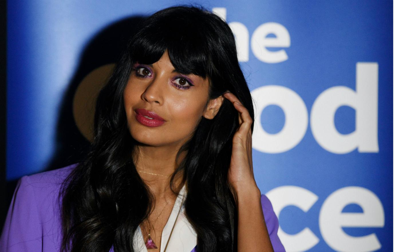 Jameela Jamil wears a lilac jacket over a white blouse on the red carpet.