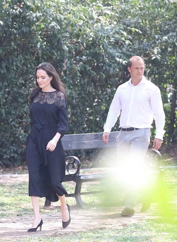 Angelina Jolie is all smiles as she steps out in Cambodia with a handsome mystery man, who has also been bonding with her six young children and buying her jewelry.