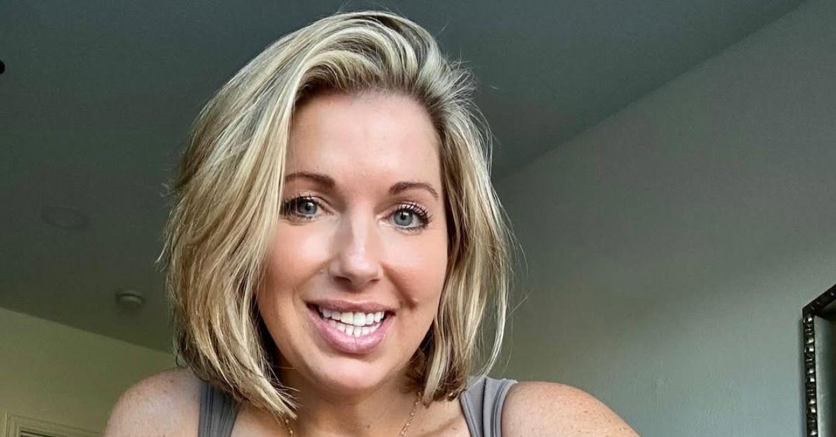 Courtney Ann smiles in a close-up photo, wearing a sleeveless top with her blonde bob styled casually around her face.